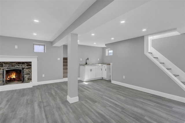 below grade area with baseboards, stairway, wood finished floors, a fireplace, and recessed lighting