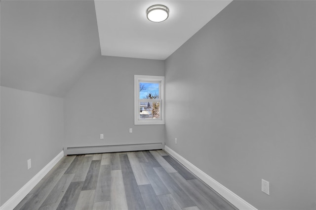 bonus room with a baseboard heating unit, vaulted ceiling, baseboards, and wood finished floors