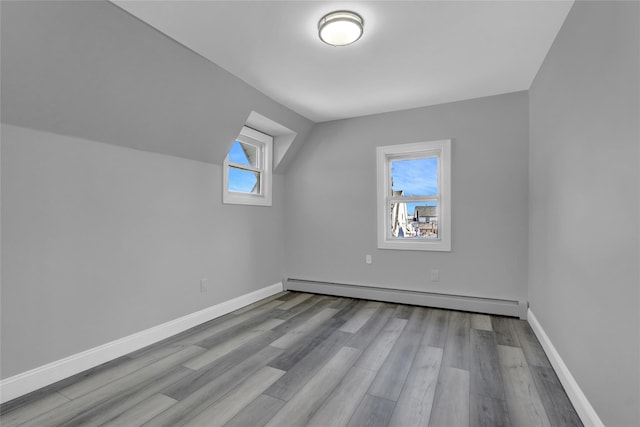 bonus room featuring vaulted ceiling, a baseboard radiator, wood finished floors, and baseboards