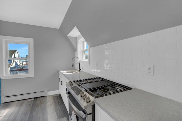 kitchen with lofted ceiling, a baseboard heating unit, wood finished floors, a sink, and stainless steel range with gas stovetop