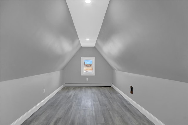 bonus room with vaulted ceiling, baseboards, baseboard heating, and wood finished floors