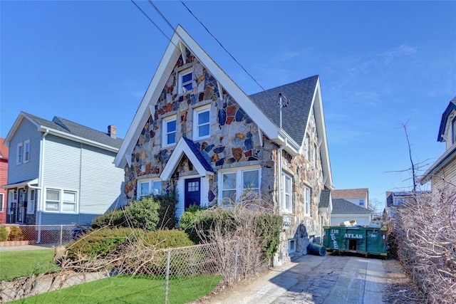 view of front of property featuring stone siding and fence