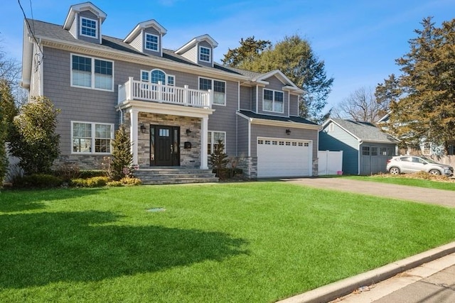 view of front facade with a front yard, stone siding, a balcony, and concrete driveway