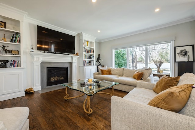 living area with a fireplace with flush hearth, built in shelves, crown molding, and hardwood / wood-style floors