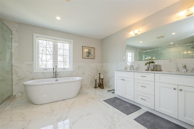 bathroom featuring double vanity, a marble finish shower, marble finish floor, a freestanding tub, and a sink