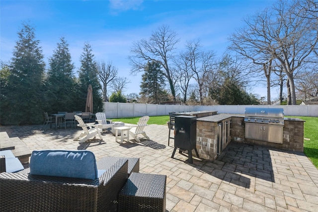 view of patio with a fenced backyard, outdoor dry bar, exterior kitchen, grilling area, and outdoor dining space