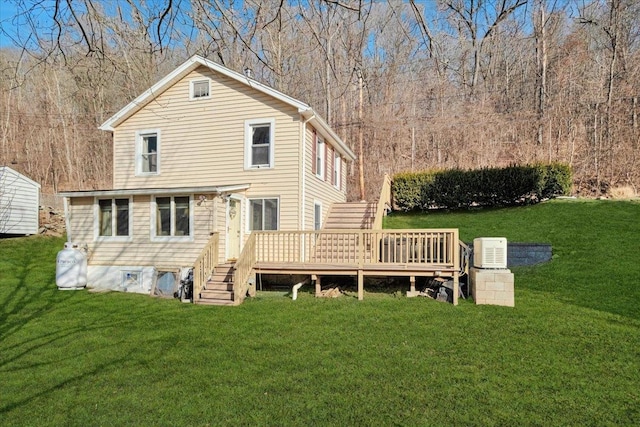 rear view of house featuring a wooden deck, a view of trees, a lawn, and stairs