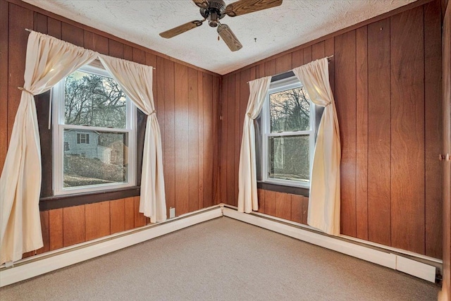 empty room with wooden walls, a baseboard radiator, a textured ceiling, and carpet floors