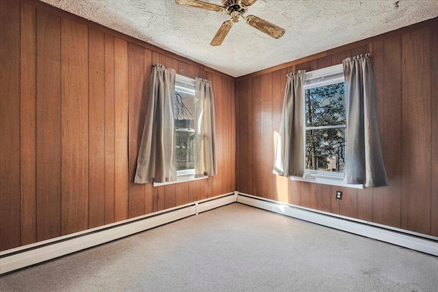 carpeted empty room with ceiling fan, wood walls, and a textured ceiling