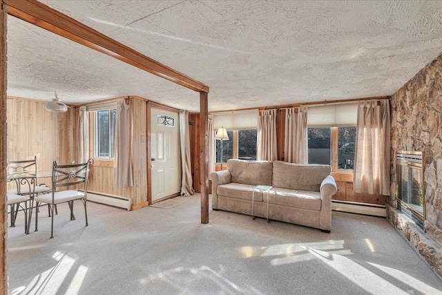 carpeted living room featuring a wealth of natural light, baseboard heating, wood walls, and a textured ceiling