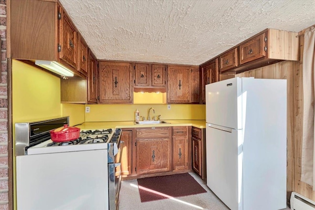 kitchen featuring a baseboard heating unit, brown cabinetry, white appliances, a textured ceiling, and a sink