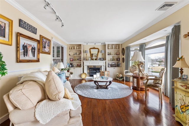 living room with visible vents, hardwood / wood-style flooring, rail lighting, crown molding, and a fireplace