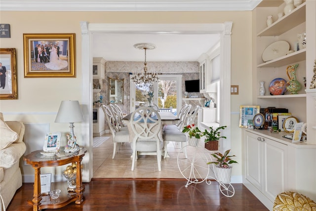 dining area with baseboards, built in features, an inviting chandelier, dark wood finished floors, and crown molding