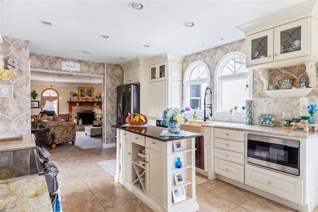 kitchen with a fireplace, open shelves, cream cabinets, open floor plan, and built in microwave