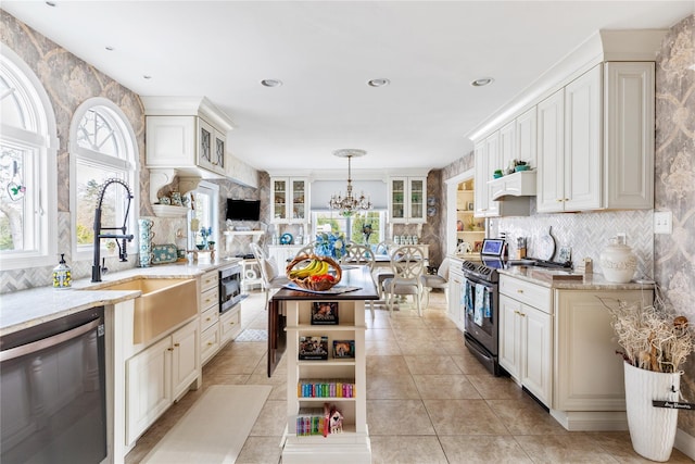 kitchen with light tile patterned floors, light stone counters, stainless steel appliances, a sink, and tasteful backsplash