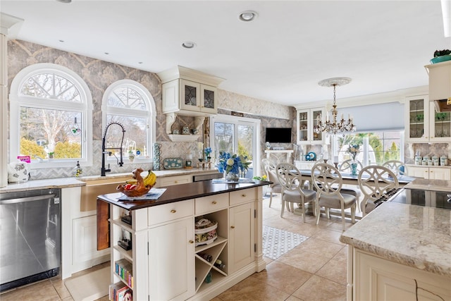 kitchen featuring a chandelier, stainless steel dishwasher, cream cabinetry, a center island, and open shelves