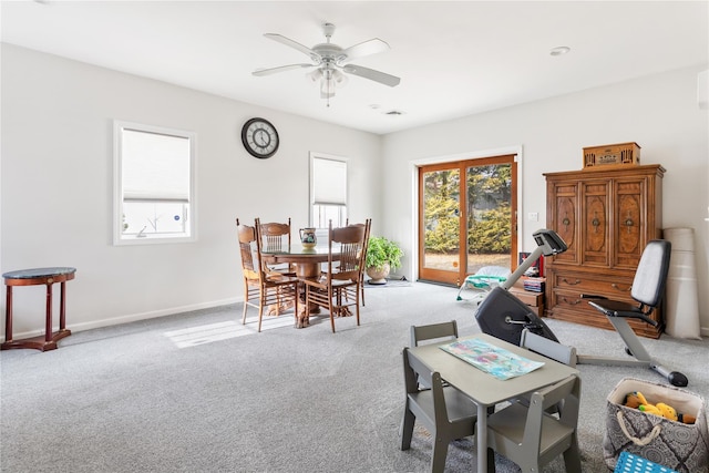 dining room with a ceiling fan, light colored carpet, and baseboards