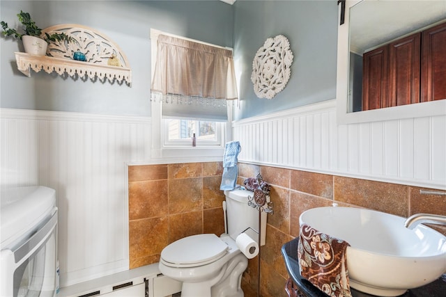 bathroom with toilet, a sink, and wainscoting