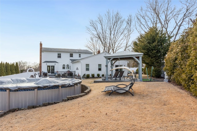 rear view of house featuring a gazebo, a chimney, and a covered pool