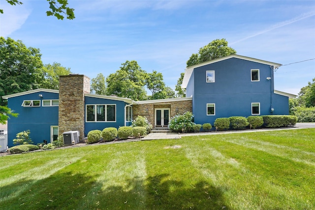 view of front of house with stone siding, stucco siding, french doors, central air condition unit, and a front yard