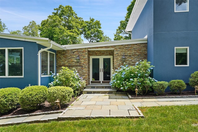 property entrance with stone siding, french doors, and stucco siding