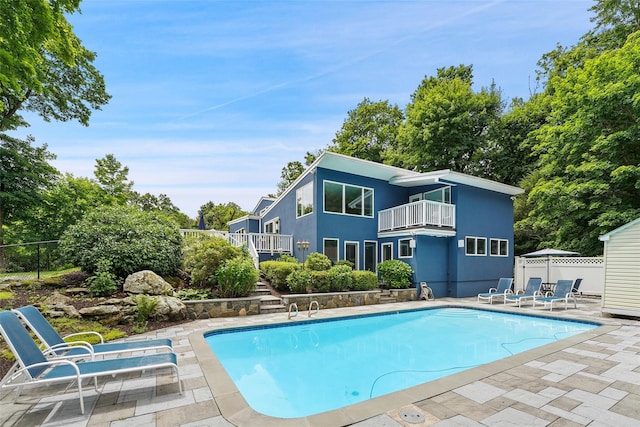 back of property with a patio, a balcony, fence, a fenced in pool, and stucco siding