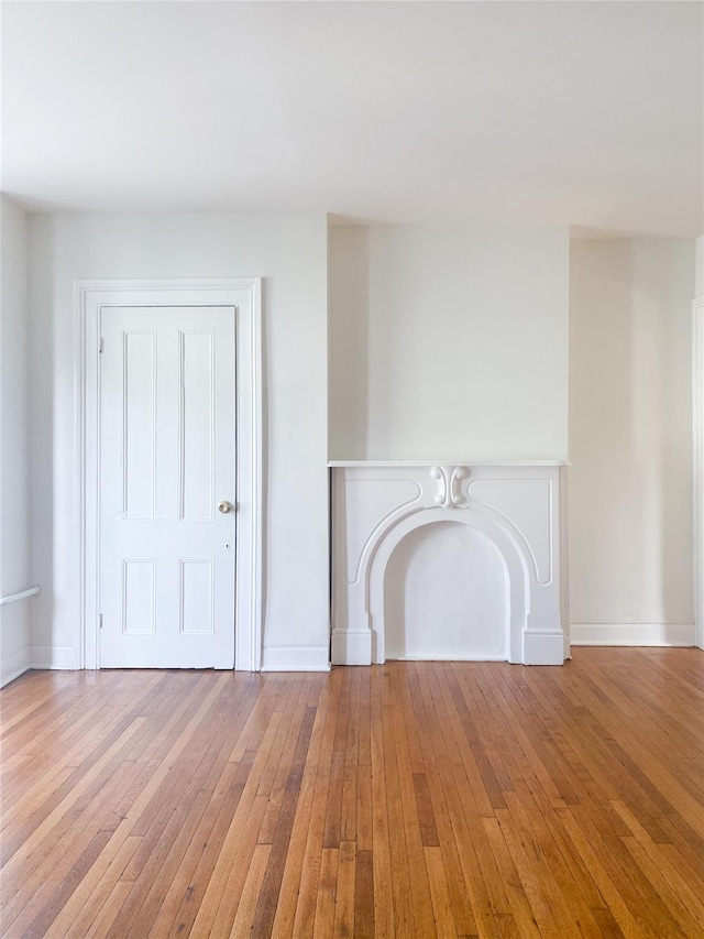 unfurnished living room featuring baseboards and hardwood / wood-style flooring