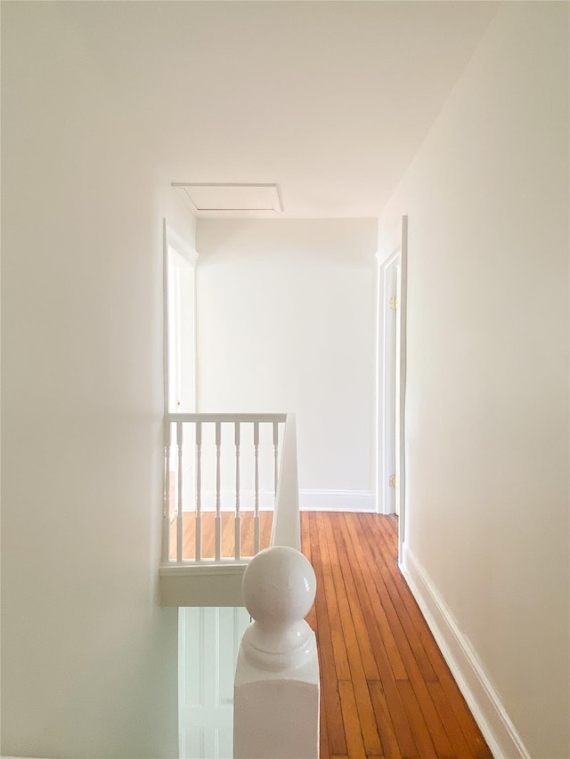 hallway featuring light wood-style floors, attic access, and baseboards