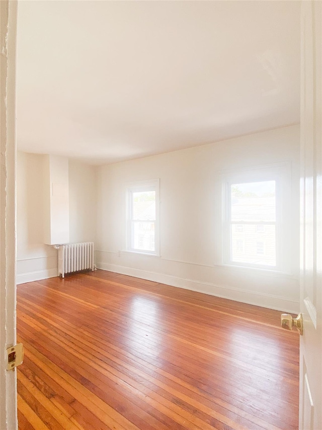 spare room featuring baseboards, light wood finished floors, and radiator heating unit