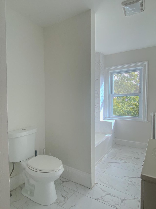 bathroom with marble finish floor, toilet, vanity, baseboards, and a bath