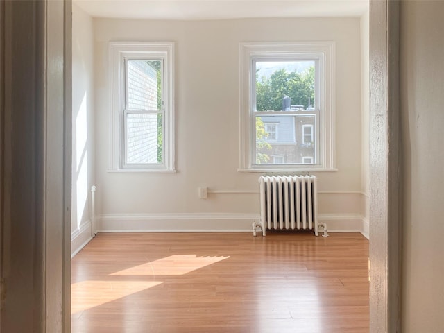 spare room with light wood-type flooring, radiator, and baseboards