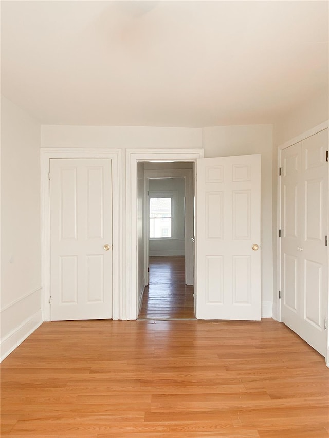 corridor featuring light wood-style floors and baseboards