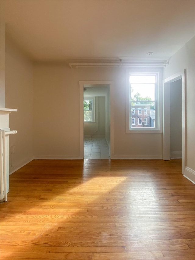 spare room with light wood finished floors, a fireplace, and baseboards