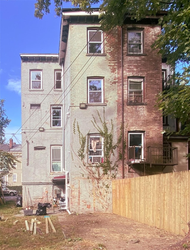 back of house with brick siding and fence