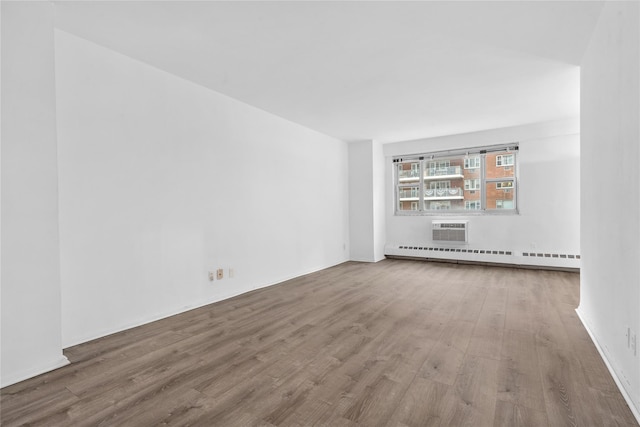 spare room featuring a baseboard radiator, a wall mounted AC, and wood finished floors