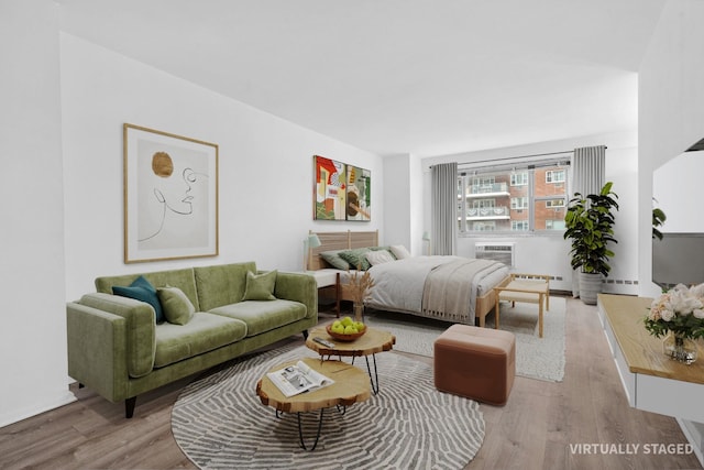 bedroom featuring a wall mounted AC, a baseboard radiator, and wood finished floors