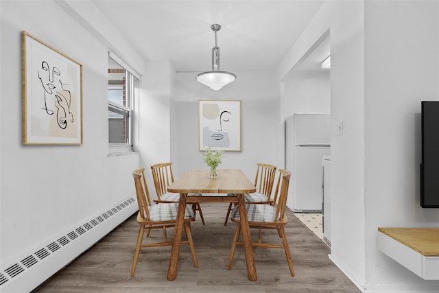 dining room with a baseboard heating unit and wood finished floors