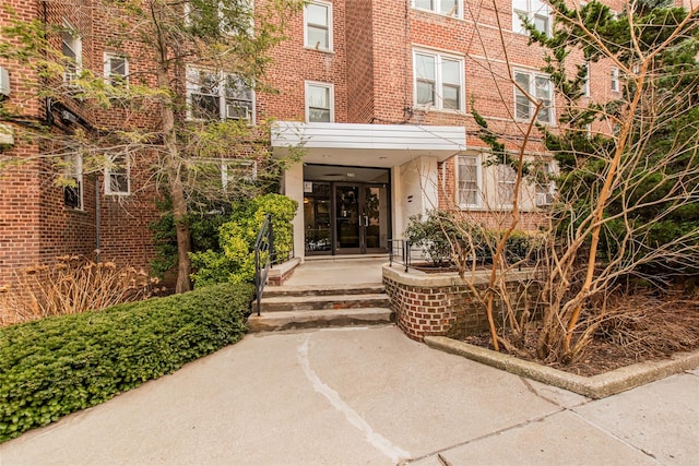 view of exterior entry featuring french doors and brick siding