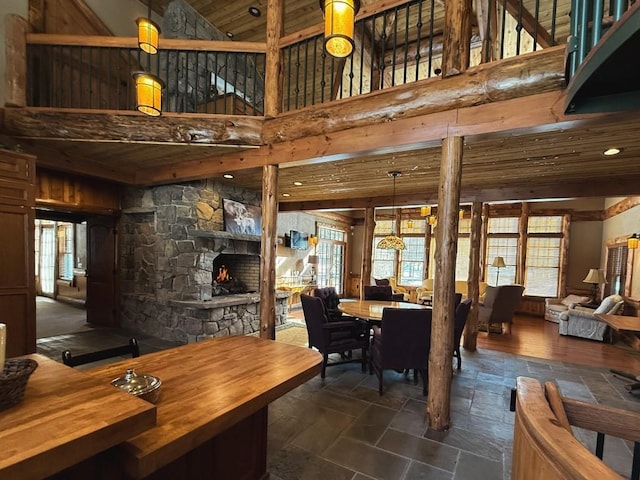 dining space with stone finish flooring, a high ceiling, a fireplace, and a wealth of natural light