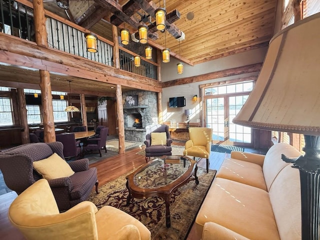 living area featuring high vaulted ceiling, wood ceiling, a fireplace, and wood finished floors