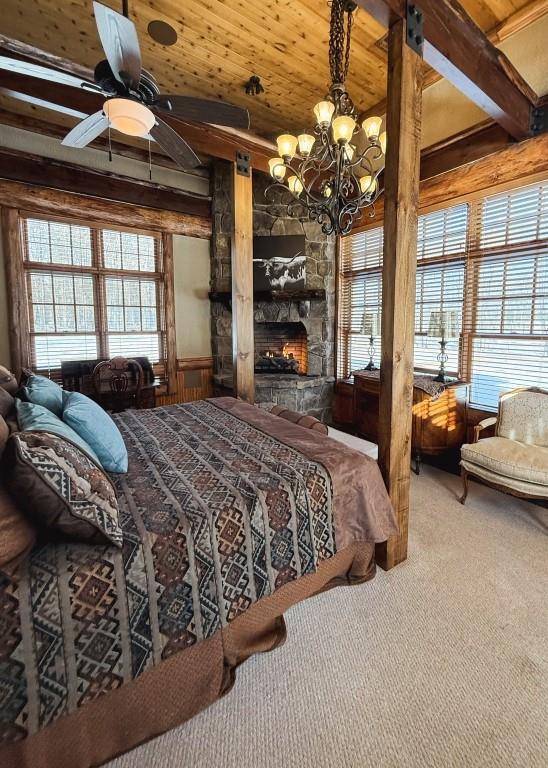 carpeted bedroom with wooden ceiling, multiple windows, a fireplace, and beam ceiling