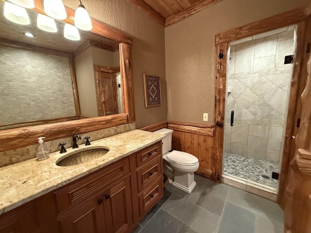 bathroom featuring a stall shower, toilet, a wainscoted wall, vanity, and wood walls