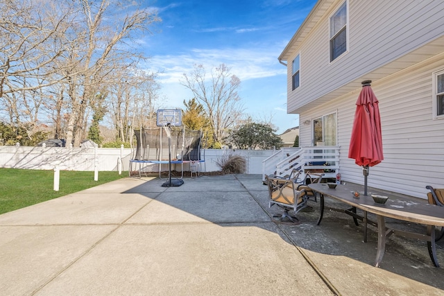 view of patio with a trampoline and fence