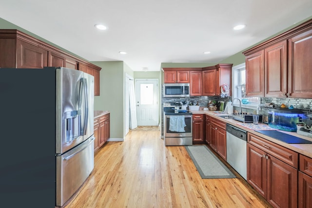 kitchen featuring light wood-type flooring, decorative backsplash, stainless steel appliances, and light countertops