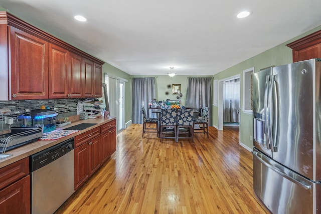 kitchen with stainless steel appliances, light countertops, light wood-style flooring, and tasteful backsplash