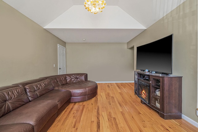 living room with light wood-type flooring, an inviting chandelier, baseboards, and vaulted ceiling