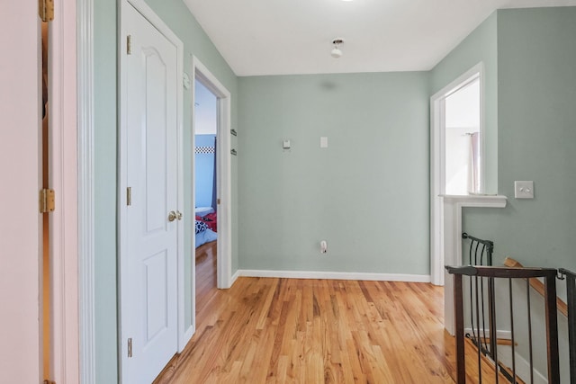 hallway featuring light wood-style flooring and baseboards