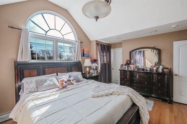 bedroom with a closet, high vaulted ceiling, baseboard heating, and wood finished floors