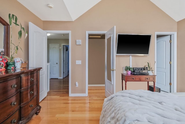 bedroom with light wood-type flooring, baseboards, and vaulted ceiling