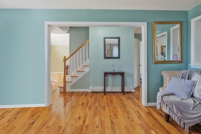 living area with baseboards, stairs, a baseboard heating unit, and wood finished floors